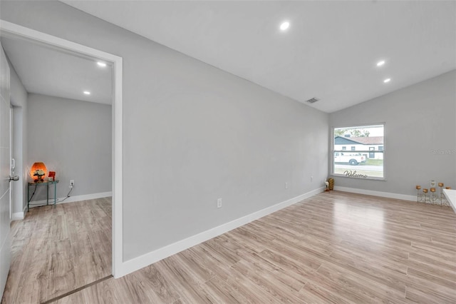 unfurnished room featuring lofted ceiling and light hardwood / wood-style flooring