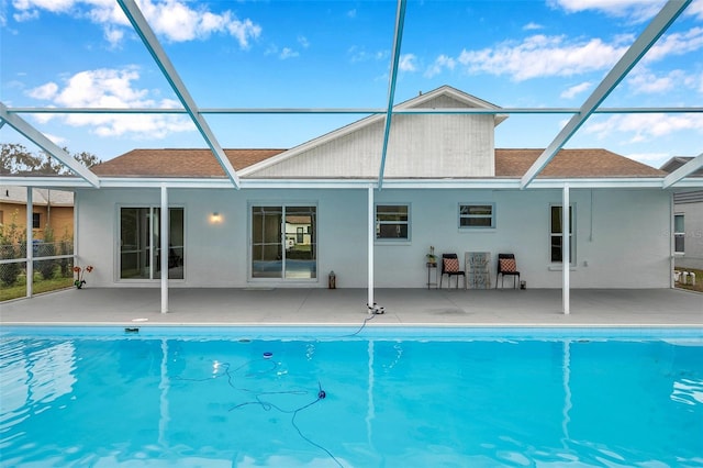 rear view of property featuring glass enclosure and a patio