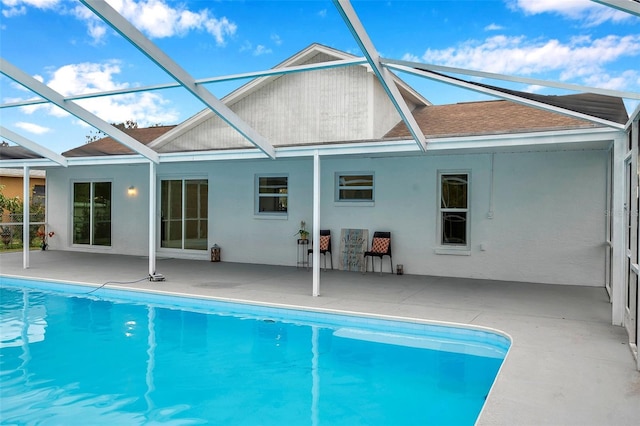 view of pool with glass enclosure and a patio