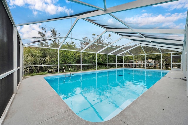 view of pool featuring glass enclosure and a patio area