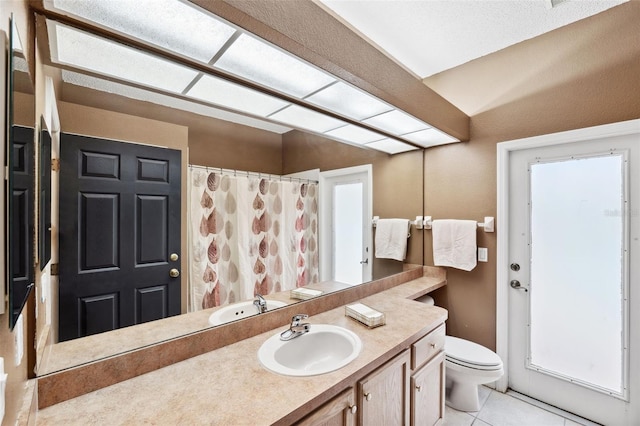 bathroom with tile patterned floors, vanity, toilet, and walk in shower