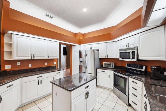 kitchen featuring white cabinetry, light tile patterned floors, stainless steel appliances, and a textured ceiling