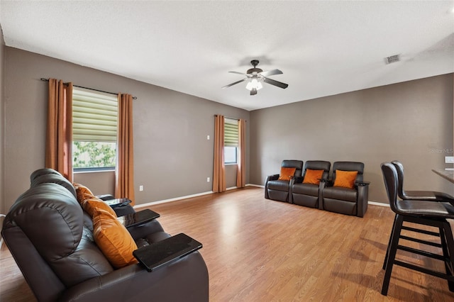 living room with ceiling fan, a textured ceiling, and light hardwood / wood-style flooring