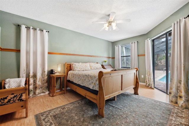 bedroom with ceiling fan, a textured ceiling, hardwood / wood-style flooring, and access to outside