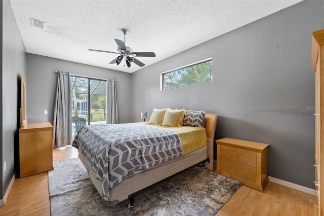 bedroom featuring a textured ceiling, ceiling fan, light hardwood / wood-style flooring, and access to outside