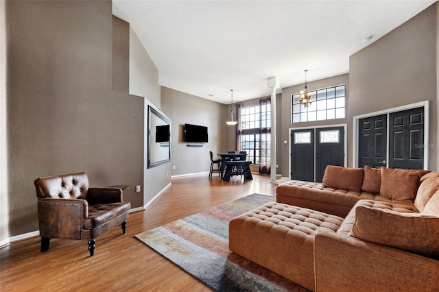 living room with light hardwood / wood-style floors, a towering ceiling, and an inviting chandelier