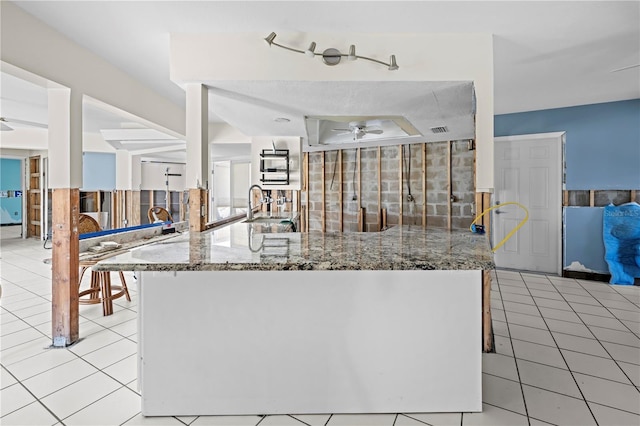 kitchen featuring stone counters, light tile patterned flooring, and sink