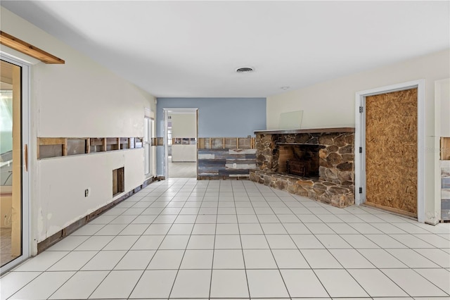 unfurnished living room with light tile patterned floors and a stone fireplace