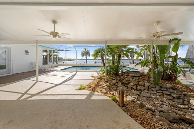 view of swimming pool featuring glass enclosure, a patio area, and ceiling fan