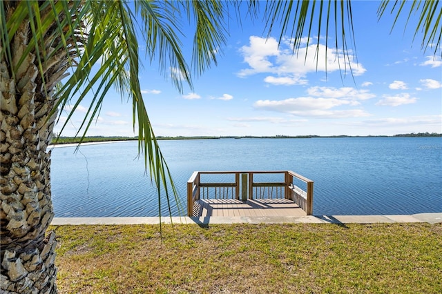 view of dock with a yard and a water view