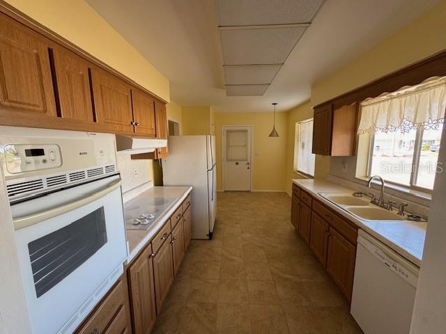 kitchen with sink, hanging light fixtures, and white appliances