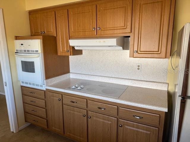 kitchen with white oven, stainless steel fridge, tile patterned floors, and electric cooktop