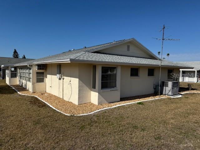 view of side of home featuring central AC and a lawn