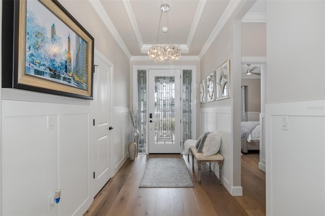 foyer entrance featuring crown molding, hardwood / wood-style flooring, and ceiling fan with notable chandelier