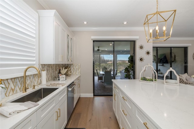 kitchen featuring sink, dishwasher, white cabinetry, backsplash, and light stone countertops