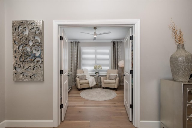 living area with crown molding, light hardwood / wood-style flooring, and ceiling fan