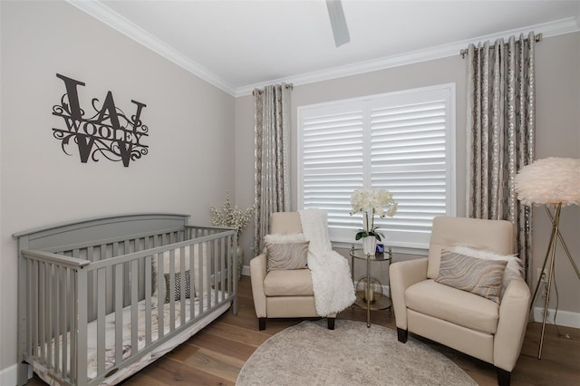 bedroom featuring hardwood / wood-style flooring, ceiling fan, crown molding, and a crib