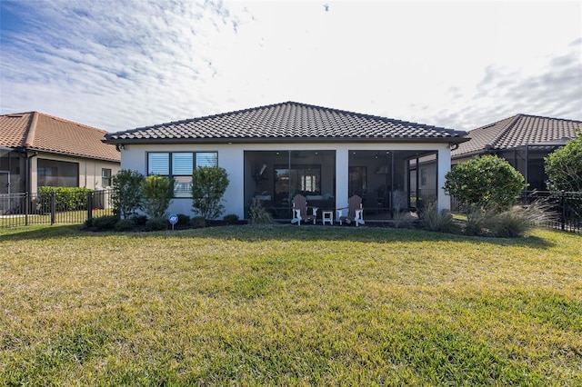 rear view of house featuring a sunroom and a lawn