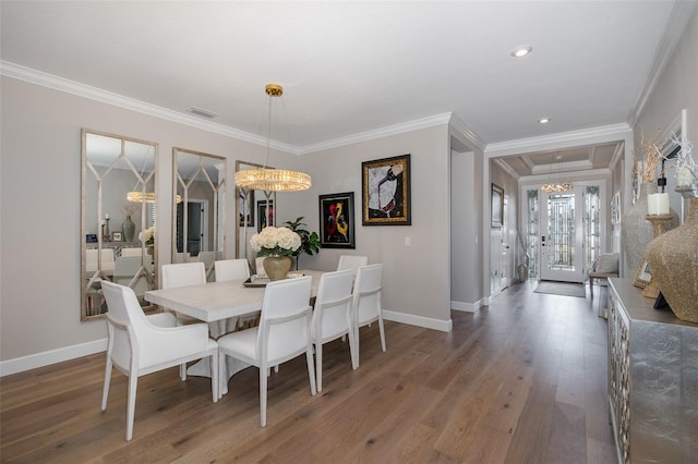 dining space with an inviting chandelier, ornamental molding, and dark wood-type flooring