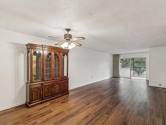 unfurnished room with a textured ceiling, dark wood-type flooring, and ceiling fan