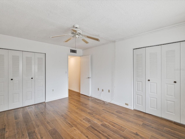 unfurnished bedroom featuring ceiling fan, a textured ceiling, and dark hardwood / wood-style flooring