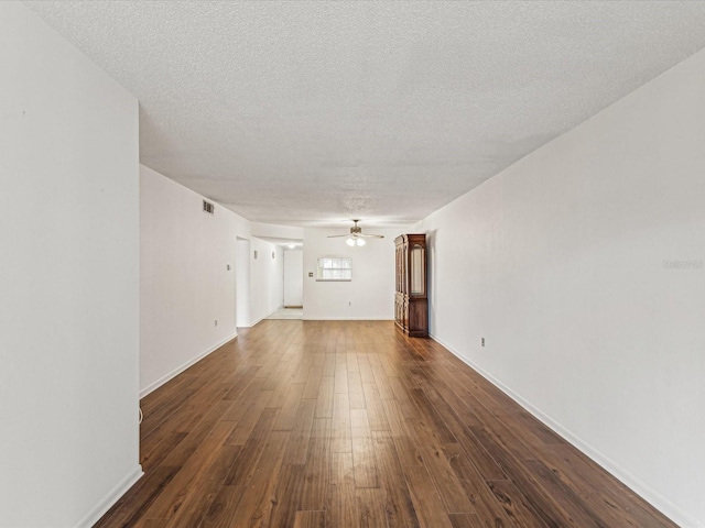 unfurnished living room featuring ceiling fan, dark hardwood / wood-style floors, and a textured ceiling