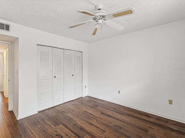 unfurnished bedroom featuring a closet, dark hardwood / wood-style floors, a textured ceiling, and ceiling fan