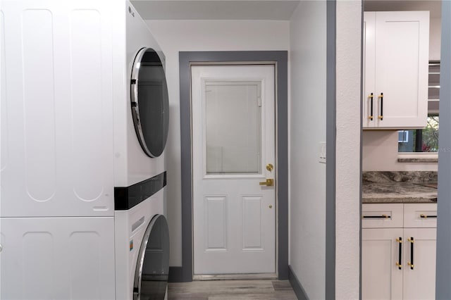 clothes washing area featuring stacked washer / dryer and light wood-type flooring