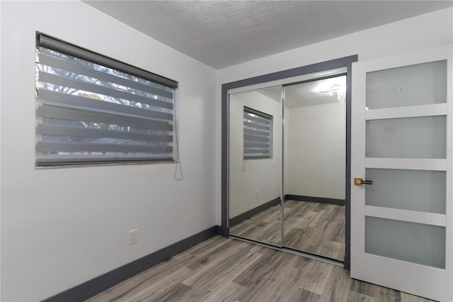 unfurnished bedroom featuring a textured ceiling, a closet, and wood-type flooring