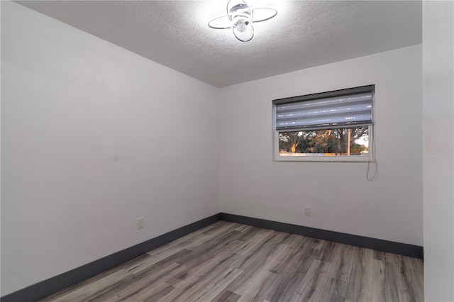 empty room with a textured ceiling and wood-type flooring