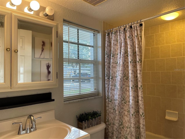 full bathroom featuring vanity, shower / bathtub combination with curtain, a textured ceiling, and toilet