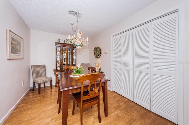 dining space with a notable chandelier, light hardwood / wood-style flooring, and a textured ceiling