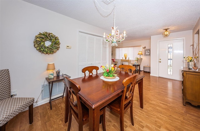 dining room featuring a notable chandelier, a textured ceiling, and light wood-type flooring