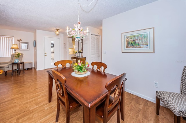 dining room with an inviting chandelier, a textured ceiling, and light hardwood / wood-style floors