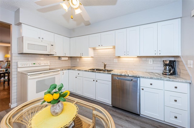 kitchen with sink, white appliances, dark wood-type flooring, white cabinetry, and light stone counters