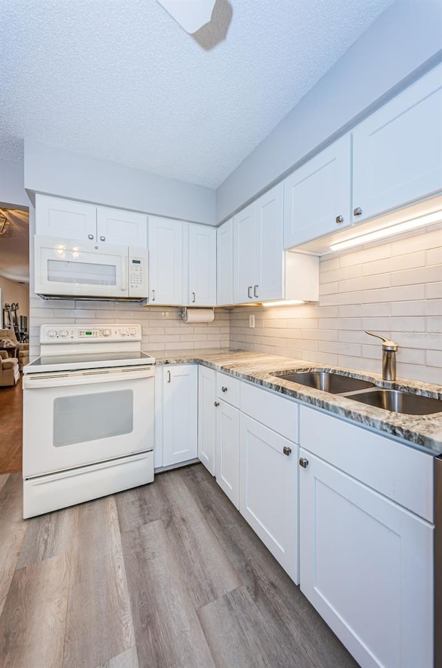 kitchen featuring white appliances, sink, light hardwood / wood-style flooring, and white cabinets