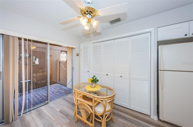 dining room featuring ceiling fan, a textured ceiling, and light wood-type flooring