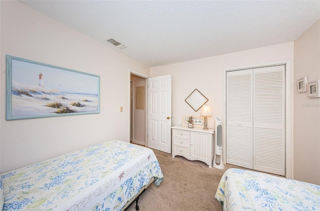 bedroom featuring light carpet, a textured ceiling, and a closet