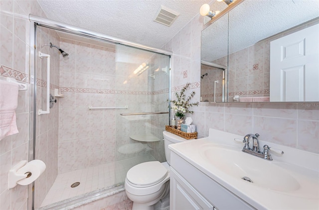 bathroom with vanity, an enclosed shower, tile walls, and a textured ceiling