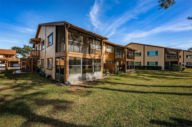 rear view of property featuring a yard and a sunroom