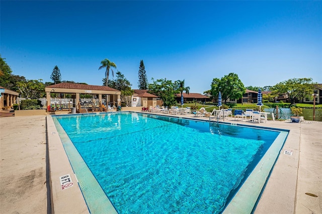 view of swimming pool featuring a gazebo, a water view, and a patio