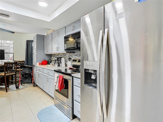 kitchen featuring stainless steel appliances, light tile patterned floors, gray cabinetry, and decorative backsplash