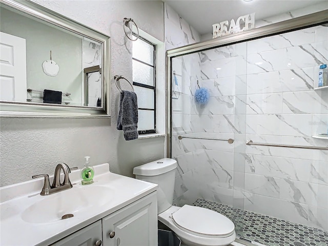 bathroom featuring vanity, toilet, and a shower with door