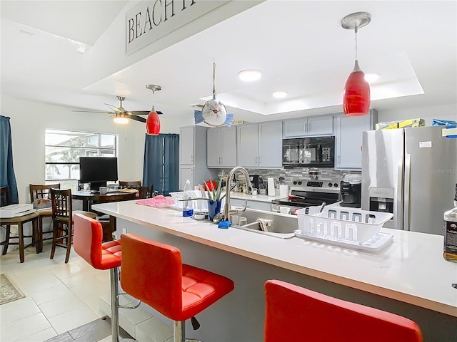 12529 Shadow Ridge Blvd, Hudson, FL 34669 - kitchen with stainless steel appliances, a tray ceiling, backsplash, hanging light fixtures, and a breakfast bar