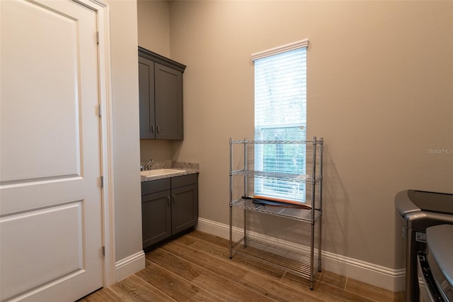 laundry area with sink, hardwood / wood-style floors, cabinets, and independent washer and dryer