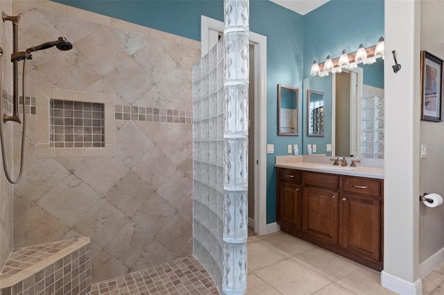 bathroom featuring tile patterned flooring, vanity, and a tile shower