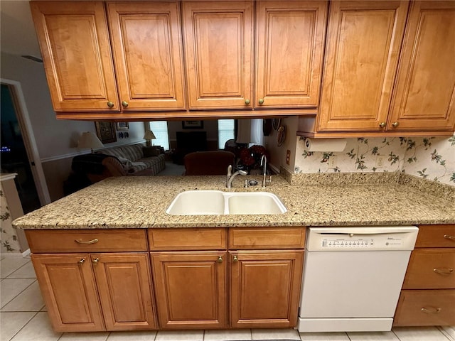 kitchen with light stone counters, dishwasher, sink, and light tile patterned floors