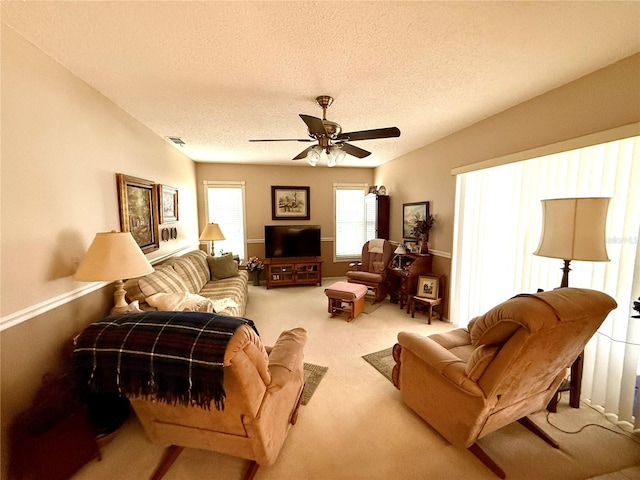 carpeted living room featuring ceiling fan and a textured ceiling