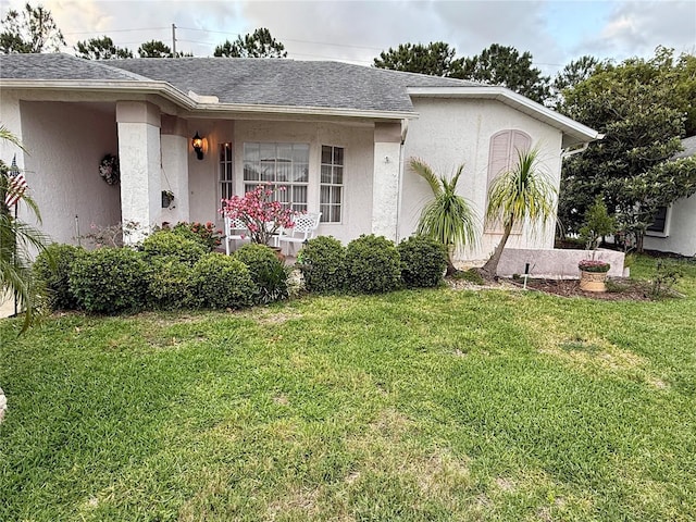 8111 Merrimac Dr, Port Richey, FL 34668 - view of front facade with a front yard, stucco siding, and roof with shingles