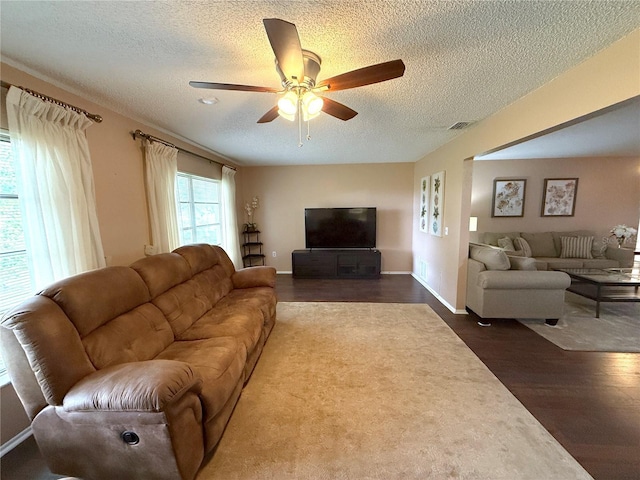 living room featuring dark hardwood / wood-style flooring, ceiling fan, and a textured ceiling